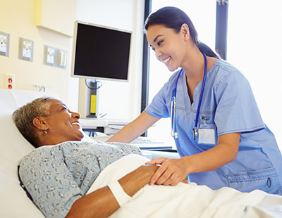 Asian nursing assistant with elderly patient in bed