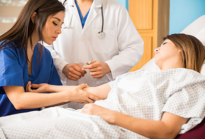 Nursing assistant helping doctor with patient in bed