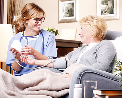 Nursing assistant taking blood pressure of a patient in bed